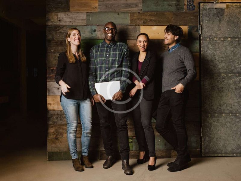 Portrait of young professionals laughing while standing together in office. Multi ethnic business team looking happy together.